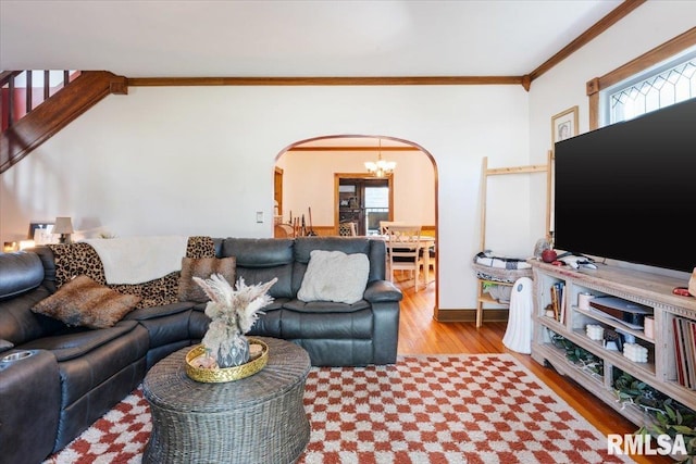 living room featuring light wood-type flooring, a chandelier, and crown molding