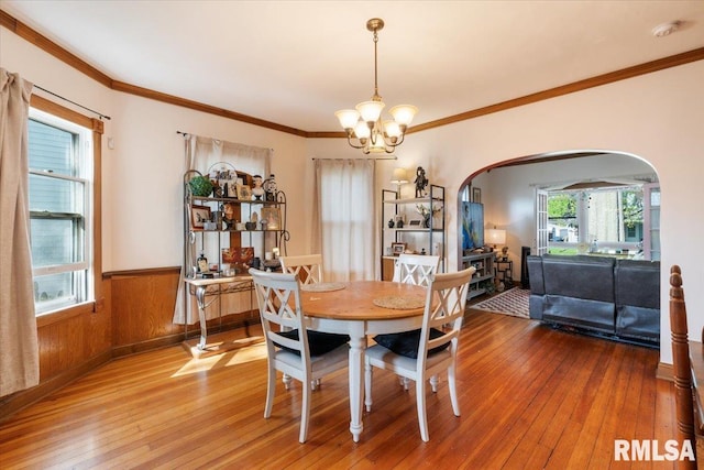 dining room featuring plenty of natural light, wooden walls, hardwood / wood-style flooring, and a chandelier