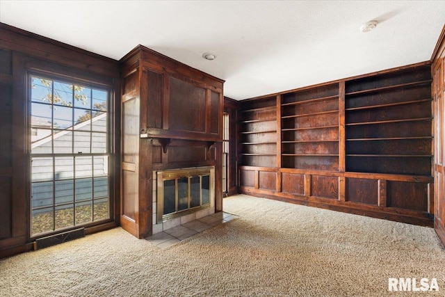 unfurnished living room featuring light colored carpet and wood walls