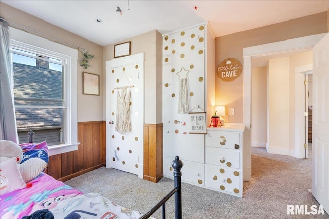 bedroom featuring light colored carpet and wood walls