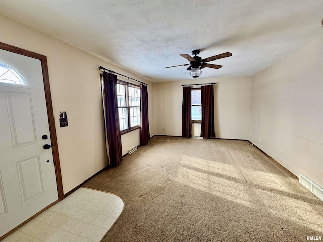 carpeted entrance foyer featuring ceiling fan and a textured ceiling