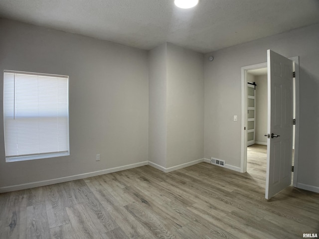 empty room featuring a textured ceiling and light wood-type flooring