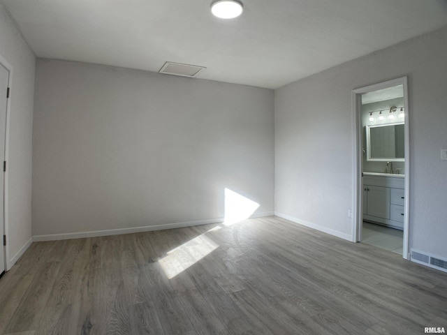 unfurnished bedroom with connected bathroom and light hardwood / wood-style floors