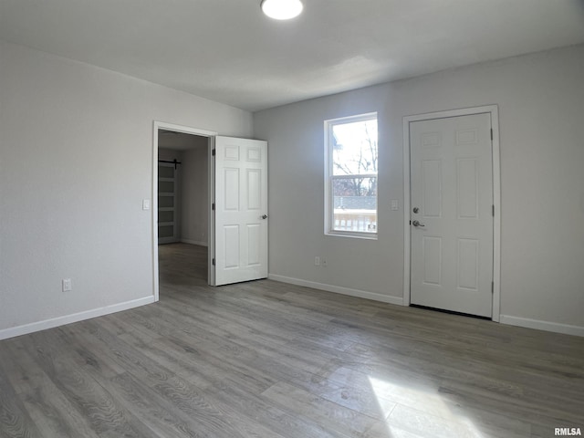 empty room with light wood-type flooring and a barn door