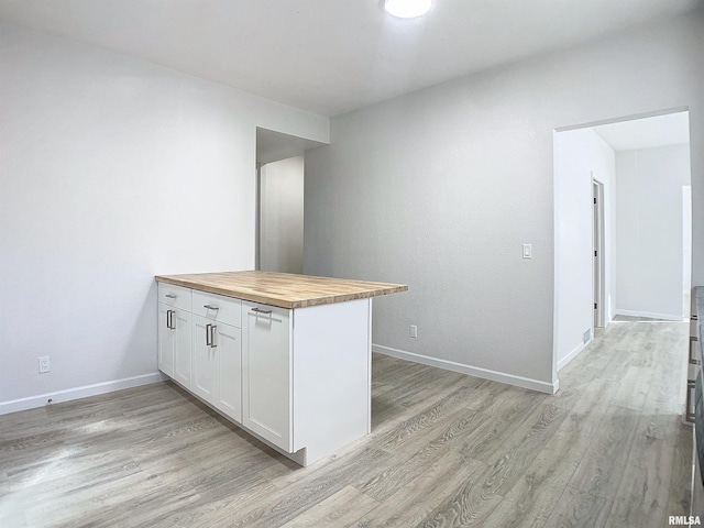 kitchen with wooden counters, white cabinets, kitchen peninsula, and light hardwood / wood-style flooring