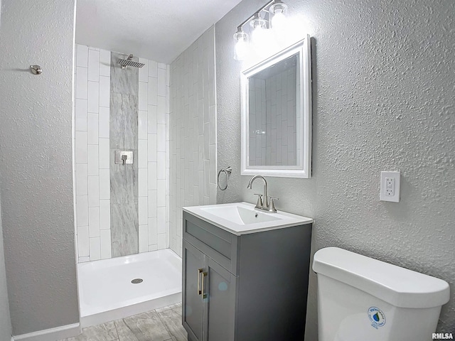 bathroom with tiled shower, vanity, and toilet