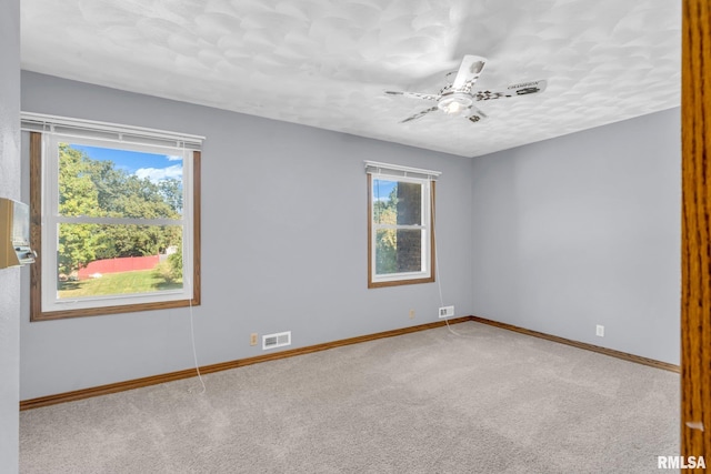 unfurnished room featuring carpet flooring, plenty of natural light, and ceiling fan