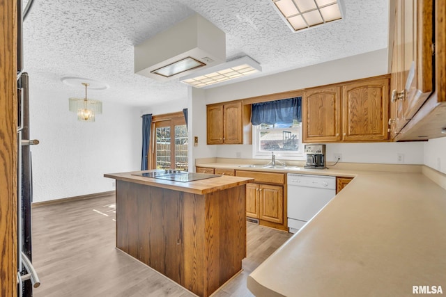 kitchen featuring black electric cooktop, dishwasher, light hardwood / wood-style floors, a kitchen island, and hanging light fixtures