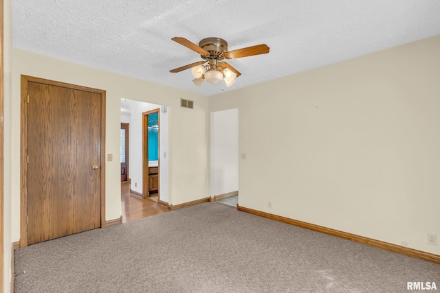 unfurnished bedroom with light carpet, a textured ceiling, a closet, and ceiling fan