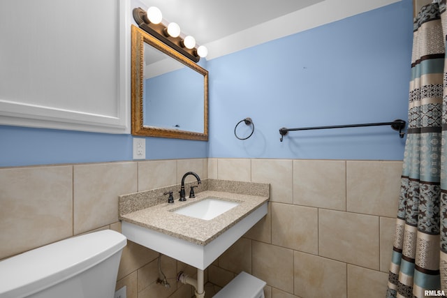 bathroom with sink, tile walls, and toilet