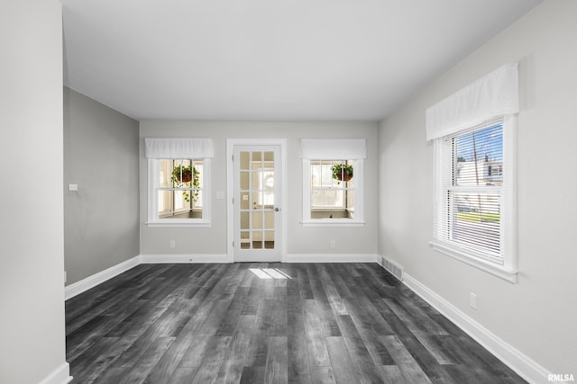 spare room with a wealth of natural light and dark hardwood / wood-style floors