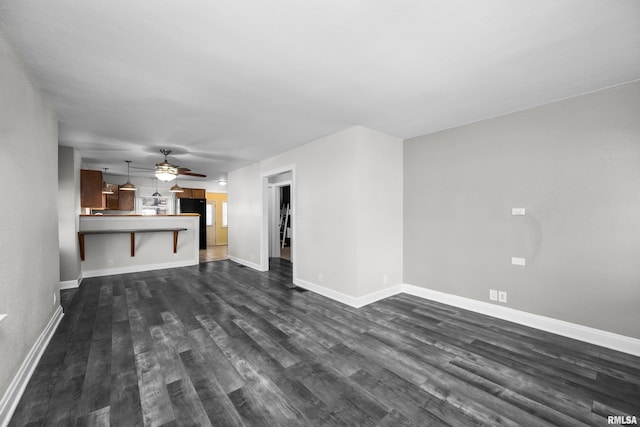 unfurnished living room with dark hardwood / wood-style flooring and ceiling fan