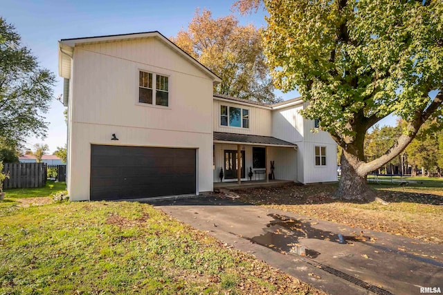 view of front of home with a garage, a front yard, and a porch