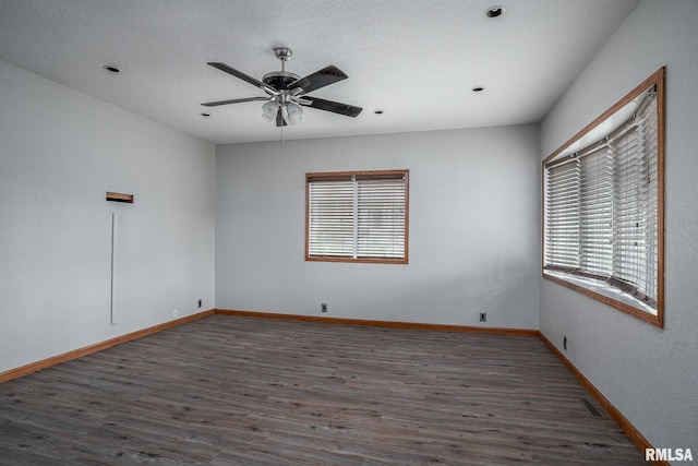 spare room with ceiling fan, dark wood-type flooring, a healthy amount of sunlight, and a textured ceiling