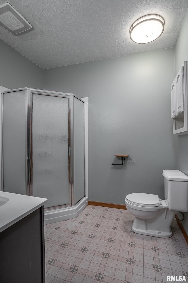 bathroom with a shower with door, vanity, a textured ceiling, and toilet