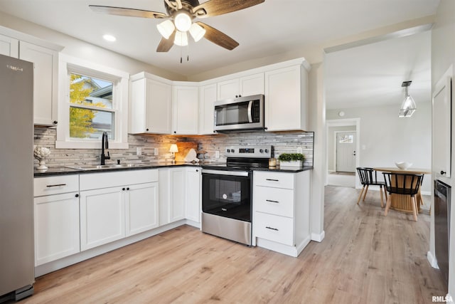 kitchen featuring appliances with stainless steel finishes, sink, light hardwood / wood-style floors, and white cabinets