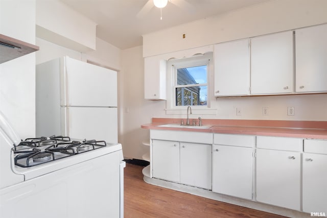 kitchen featuring white cabinetry, sink, ceiling fan, white appliances, and light wood-type flooring