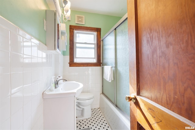 full bathroom featuring combined bath / shower with glass door, vanity, tile patterned floors, toilet, and tile walls