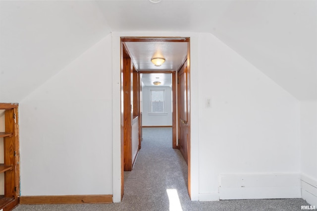 corridor with lofted ceiling and light colored carpet