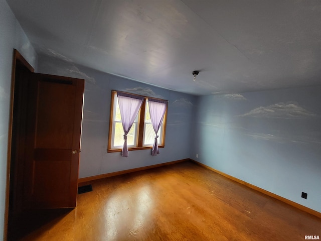 spare room with hardwood / wood-style flooring and vaulted ceiling