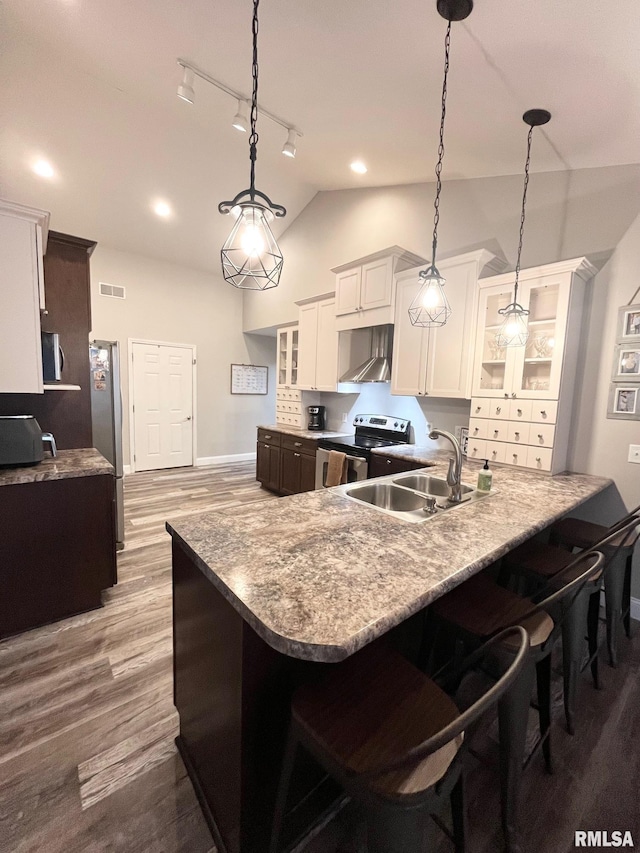 kitchen featuring sink, stainless steel appliances, kitchen peninsula, pendant lighting, and lofted ceiling