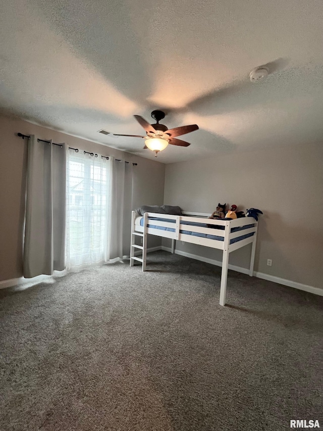 carpeted bedroom with ceiling fan and a textured ceiling