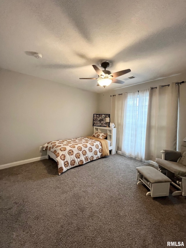 bedroom featuring dark colored carpet, ceiling fan, and a textured ceiling