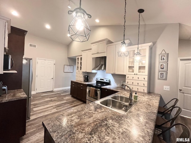 kitchen with white cabinetry, sink, hanging light fixtures, wall chimney range hood, and appliances with stainless steel finishes