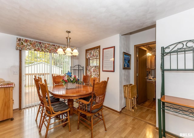 dining space featuring light wood-type flooring and an inviting chandelier