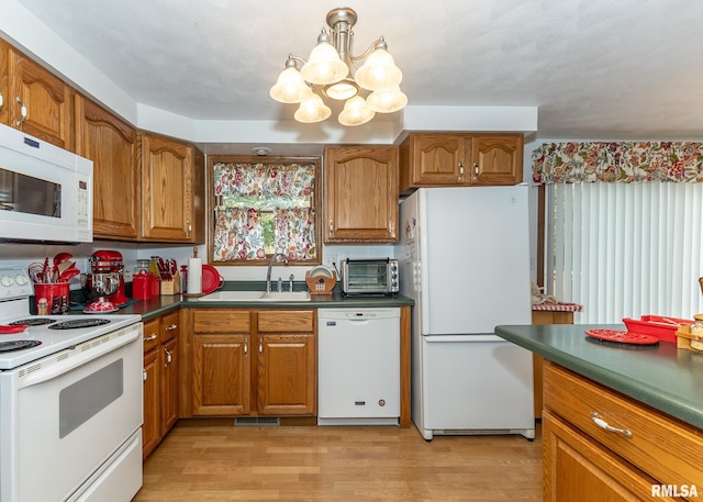 kitchen with sink, an inviting chandelier, light hardwood / wood-style flooring, pendant lighting, and white appliances