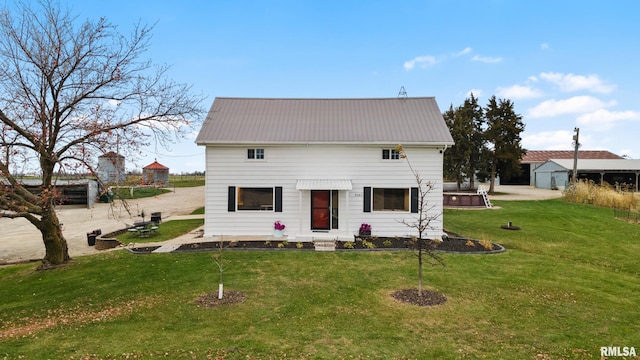 back of house featuring a yard and a hot tub