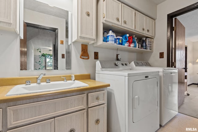 clothes washing area with washer and dryer, a textured ceiling, cabinets, and sink