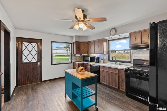 kitchen featuring black appliances, backsplash, sink, and dark wood-type flooring