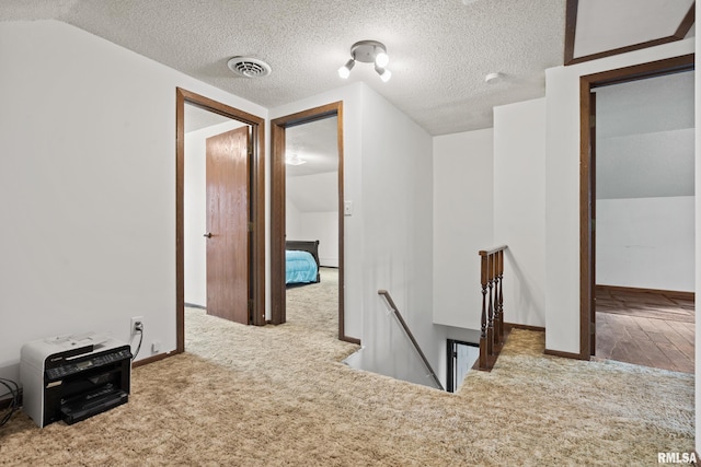 corridor featuring carpet, a textured ceiling, and vaulted ceiling