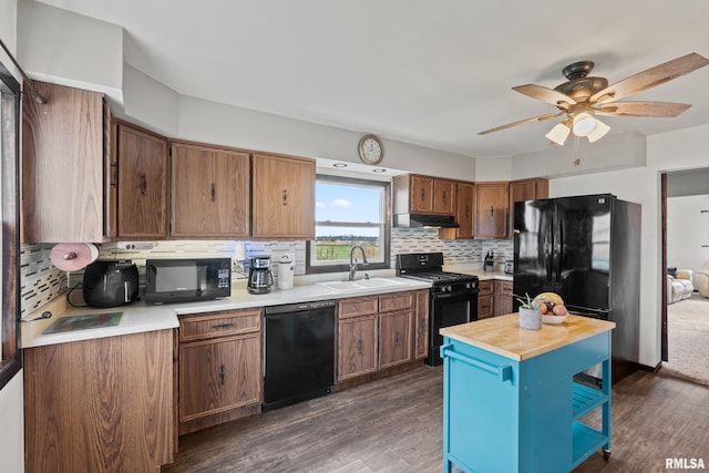 kitchen featuring black appliances, sink, dark wood-type flooring, and tasteful backsplash