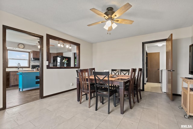 dining area with a textured ceiling, light hardwood / wood-style flooring, ceiling fan, and sink