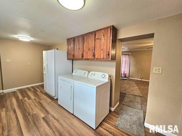 washroom with cabinets, a textured ceiling, light hardwood / wood-style floors, and washer and clothes dryer