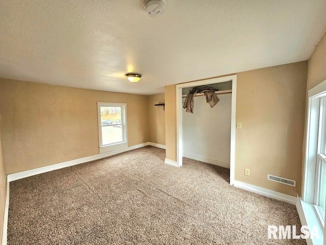 unfurnished bedroom with carpet, a textured ceiling, and a closet