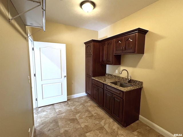 kitchen with stone counters, sink, and dark brown cabinets