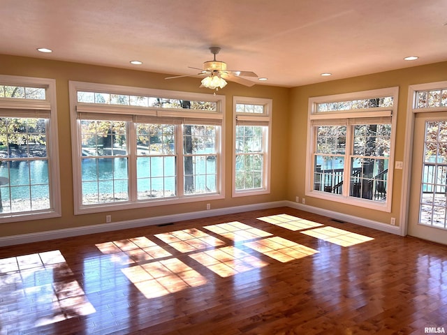 unfurnished sunroom with a water view and ceiling fan