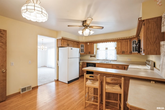 kitchen featuring kitchen peninsula, stove, white fridge, light hardwood / wood-style floors, and a breakfast bar area