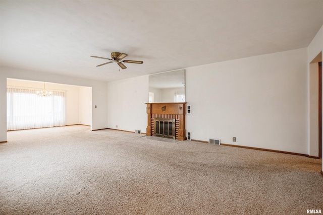 unfurnished living room featuring a fireplace, carpet floors, and ceiling fan with notable chandelier