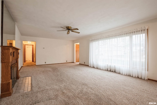 unfurnished living room featuring a tile fireplace, ceiling fan, and light colored carpet