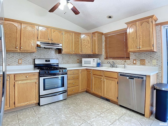 kitchen featuring decorative backsplash, appliances with stainless steel finishes, vaulted ceiling, ceiling fan, and sink