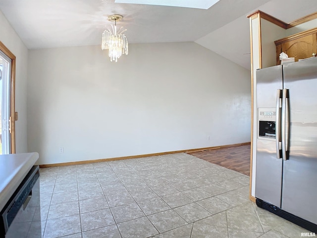 kitchen featuring stainless steel appliances, lofted ceiling with skylight, decorative light fixtures, an inviting chandelier, and light hardwood / wood-style flooring