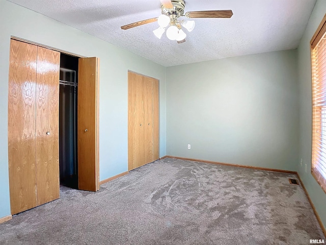 unfurnished bedroom featuring carpet, ceiling fan, a textured ceiling, and multiple windows