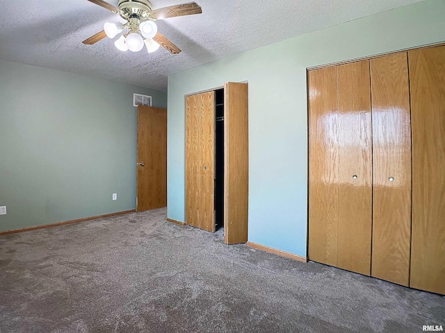 unfurnished bedroom featuring light carpet, a textured ceiling, ceiling fan, and multiple closets