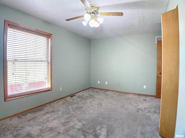 carpeted empty room featuring ceiling fan, plenty of natural light, and a textured ceiling