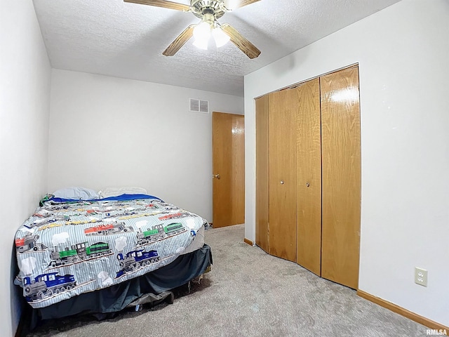 carpeted bedroom with ceiling fan, a closet, and a textured ceiling