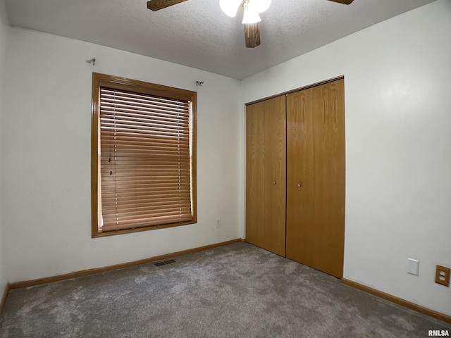 unfurnished bedroom with ceiling fan, a closet, light colored carpet, and a textured ceiling